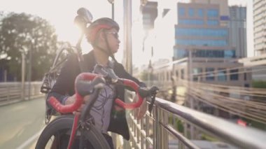 Koyu mavi takım elbiseli, güneş gözlüklü genç, merdivenlerden aşağı kötü trafiğe bakıyor ve nöbet tutuyor, zaman yolculuğunu, büyük şehirde trafik sıkışıklığını, işe bisikletle gitmeyi, favori hobi ve sağlık hayatını, kilo vermeyi düşünüyor.