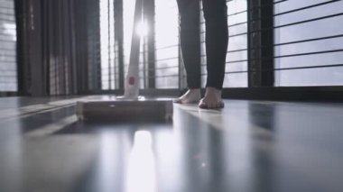Low angle shit of young female using vacuum cleaner sweeping on dusty house floor, housewife maid cleaning routine, hygiene home cleaning product, cleaner service, restart a new day, sunlight leaking, professional cleaning service, home activity 
