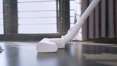 Low angle shit of young female using vacuum cleaner sweeping on dusty house floor, housewife maid cleaning routine, hygiene home cleaning product, cleaner service, restart a new day, sunlight leaking, professional cleaning service, home activity 