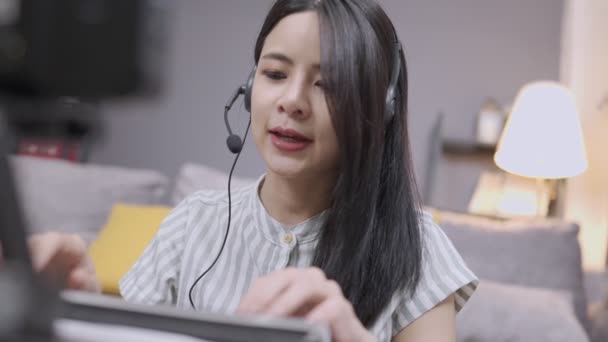アジアの若い女性は 電話会議で話してヘッドセットを着用 マイクの声の相互作用 学習Eラーニング ワイヤレスキーボードを入力 オンライン教育コース 床に自宅のリビングルームに滞在 2番目の仕事と収入 ワイヤレスインターネット接続 — ストック動画
