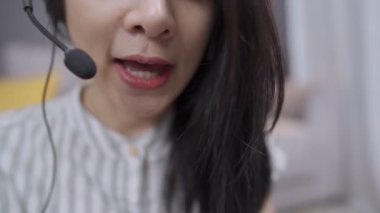 Asyalı kadın ajan çağrı merkezini yakından takip et kulaklık tak müşteriyle konferans yap, ev işçisi danışman servisi, covid-19 salgın kriz adaptasyonu, sosyal mesafe, uzaklık çevrimiçi kurslar,