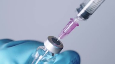 Enjeksiyon iğnesinin yakın çekimi şeffaf ilacı şırıngaya, ilacı şişeye, aşı enjeksiyonuna, serum sisteminin idaresine, koronavirüs aşısı dağıtım tedavisine dönüştürür.