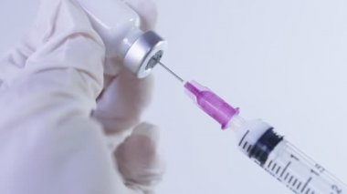 Aşı ilacını enjeksiyon iğnesine dolduran elastik beyaz koruyucu eldivenler, yeni biyoteknoloji laboratuvar araştırması, covid19 aşısı, pandemik tedavi, virüs önleme, yakın çekim