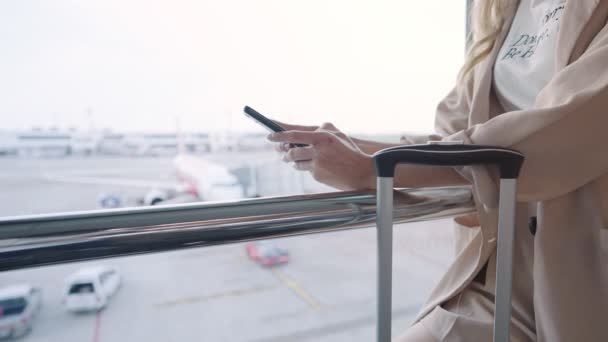 ビジネス女性の手を閉じる空港ターミナルビジネス旅行 携帯電話や旅行の荷物や飛行機の中に立って フライトを待っている間に携帯電話のテキストメッセージチャットを使用してバックグラウンドで — ストック動画