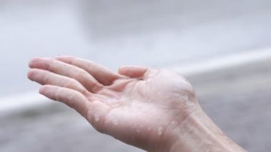 Yağmur kadın palmiyesine düşer, yağmurlu bir günde, doğaya dokunur, palmiyeye yağmur yağar, yağmurlu mevsim ağır çekimde, sokak tarafında, saf doğal su, asit yağmuru, sıvı ph ölçümü, izole edilmiş el