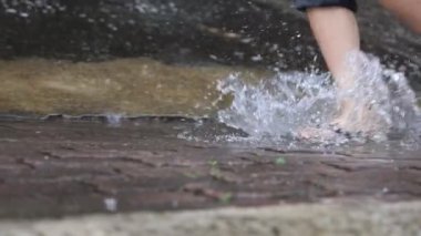 Düşük açılı ayak pozu yağmurlu yağmurlu bir günde, sel basmış bir sokakta, fırtınalı muson mevsimlerinde, ıslak ayaklar su birikintisinde, yağmurlu bir günde sırılsıklam sandaletler giyer.