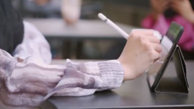 İki genç Müslüman bayan arkadaş öğleden sonra çay molasında neşeli sohbetler yapıyorlar. Restoran masasında oturup oynuyorlar. Modern İslam, tablete el çizimi, cihaz uygulama cihazı, modern yaşam tarzı, hafta sonları dinlendirici aktiviteler.