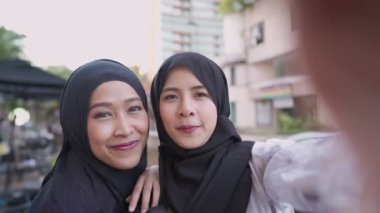 Genç, neşeli Asyalı Müslüman kadın arkadaş tesettüre girmiş, şehir trafiği kavşağında, gezinin keyfini çıkarıyor, turist gezintisinin keyfini çıkarıyor, mutlu gülüşmeler, kadınlık toplumu, hafta sonu dinlendirici aktiviteler.