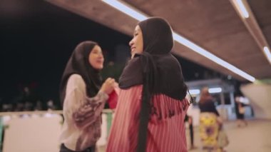 İki Asyalı neşeli Müslüman arkadaş, modern şehir yaya köprüsünde dururken vücutlarını kağıt alışveriş torbalarıyla dolduruyorlar. Kadın dinlenme aktivitesi, teftiş eden kişi ya da mikro etken, modern insanlar iyi bir ilişkiden hoşlanıyor.