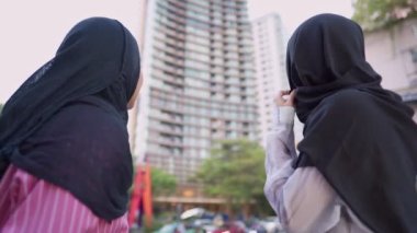 İki Asyalı Müslüman kadın alışverişe çıkıyor, arkadaşlar işten sonra bir araya geliyor, maaşlı işçi para harcıyor, arkadaşlar metropoliten yürüyüş yolunda yürüyor, alışveriş torbasını tutuyor, satış terfisi, kadınlık cemiyeti, hafta sonu dinlendirici aktiviteler.