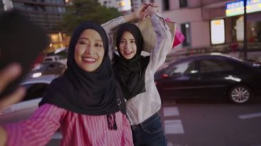 İki Asyalı Müslüman kadın alışverişe çıkıyor, arkadaşlar işten sonra bir araya geliyor, maaşlı işçi para harcıyor, arkadaşlar metropoliten yürüyüş yolunda yürüyor, alışveriş torbasını tutuyor, satış terfisi, kadınlık cemiyeti, hafta sonu dinlendirici aktiviteler.