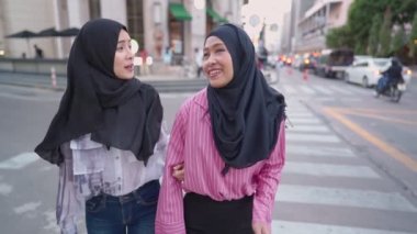 Genç, neşeli Asyalı Müslüman kadın arkadaş tesettüre girmiş, şehir trafiği kavşağında, gezinin keyfini çıkarıyor, turist gezintisinin keyfini çıkarıyor, mutlu gülüşmeler, kadınlık toplumu, hafta sonu dinlendirici aktiviteler.
