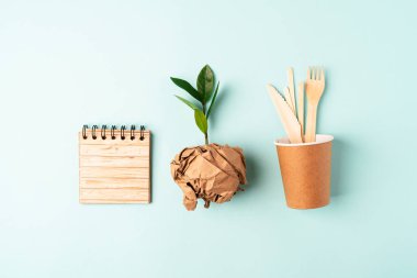 Kağıt bardak, yeşil yaprak filizi ve geri dönüşümlü çatal bıçak manzarası. Sıfır atık, çevre dostu, doğal organik plastik konsept. Masa takımı Dünya, kopyalama alanı ile biyolojik olarak çözünebilir