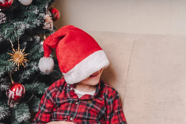모자를 귀여운 소년이 클로스가 집에서 크리스마스 트리와 거실에서 기다리고 — 스톡 사진