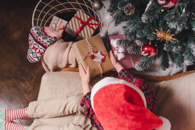 Kapalı bir Noel ağacında hediye edilen çocuk elleriyle yakın plan.