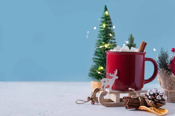 Winter hot drink, cacao with marshmallows and cinnamon or spicy hot chocolate in red cup. Merry Christmas. Festive vintage background. Copy space for text.