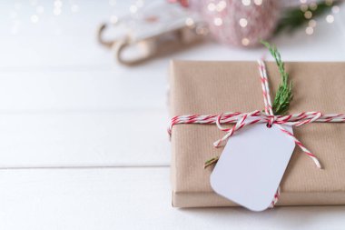 Noel hediyesi ve boş etiket. Işıl ışıl kar bokeh, kozalaklı dal. Kış tatilleri beyaz arka planda geçiyor. Sıfır atık, plastik yok