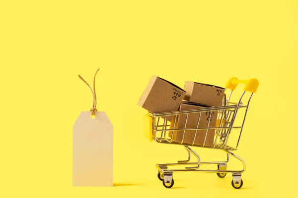 노란색 배경에는 상자와 태그가 장난감 카트가 텍스트나 디자인을 소비자 사회의 — 스톡 사진