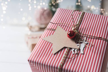 Noel hediyesi ve boş etiket. Işıl ışıl kar bokeh, kozalaklı dal. Kış tatilleri beyaz arka planda geçiyor. Sıfır atık, plastik yok. 