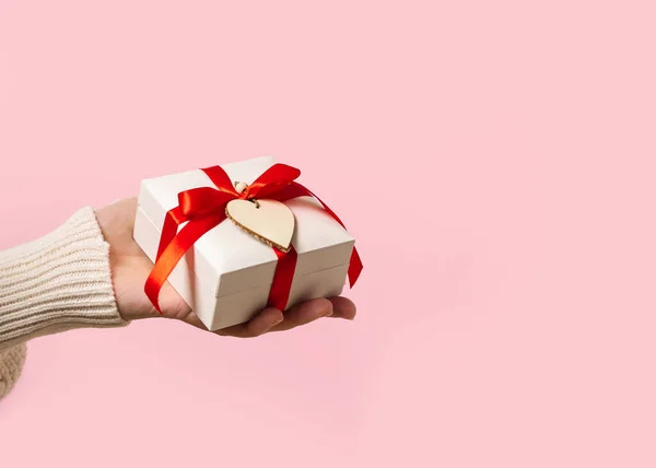 Žena ruka drží Valentine dárkové krabice na růžovém pozadí — Stock fotografie