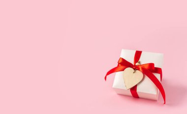 Kırmızı yay ve pembe arka planda kalp olan hediye ya da hediye kutusu. Pastel renkler, metin ve tasarım için boşluk kopyala. Sevgililer günü hediyesi. Noel bayrağı, doğum günü, doğum günü konsepti