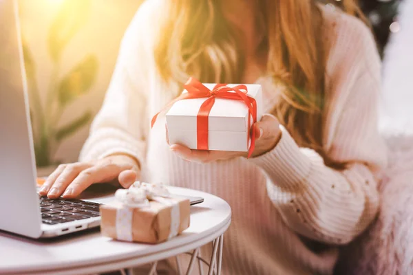 Woman holding gift typing at laptop. Holidays online shopping