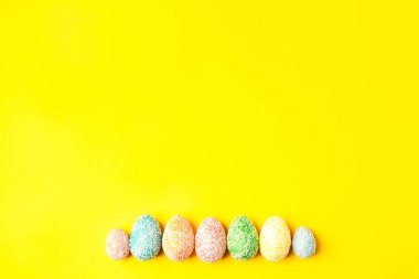 Sarı arka planda pastel yumurtalar ve metin için boşluk. Mutlu Paskalyalar.
