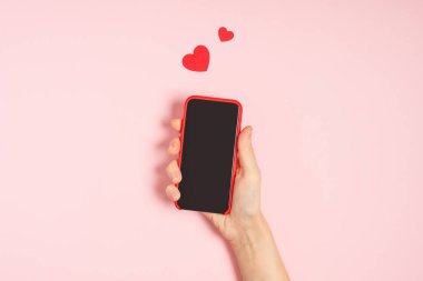 Kadın elleri cep telefonuyla kalp şeklinde boş ekran tutuyor.