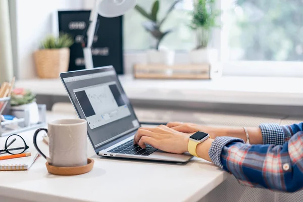 Beskuren kvinna skriver på bärbar dator när hon sitter hemma. Närbild kaffekopp och mänskliga händer. Distansutbildning på nätet och arbete. Selektiv inriktning — Stockfoto