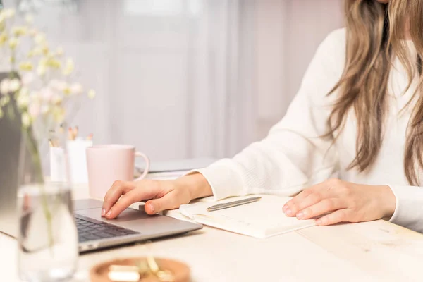 Egy nő jegyzetfüzetbe ír laptoppal az asztalon. — Stock Fotó