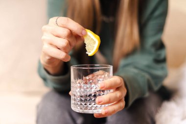 Limon dilimi ve bir bardak su tutan kadın.