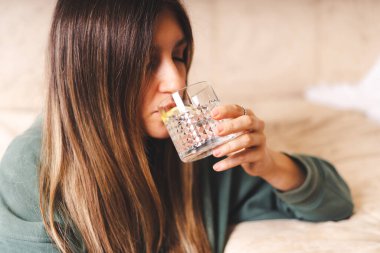 Kadın yatak odasında su içiyor.