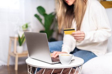 Dizüstü bilgisayarı ve kredi kartı olan bir kadın.