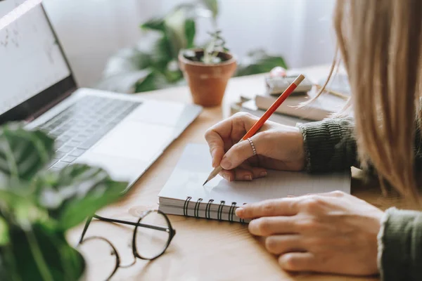 Mujer escribe en cuaderno con portátil — Foto de Stock