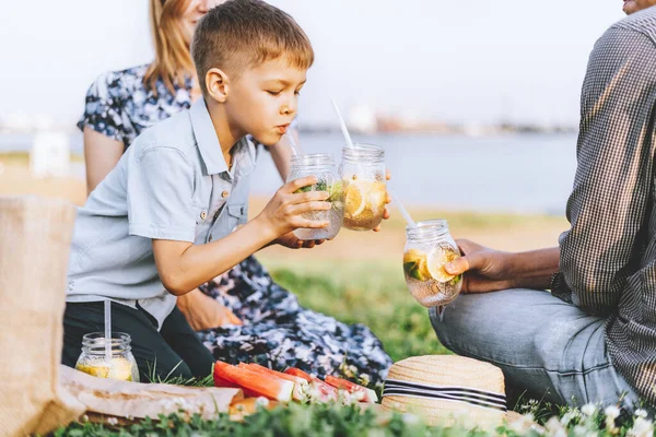 Rodzina z dzieckiem letni piknik w przyrodzie. Mały chłopiec trzymać żółte i zielone okulary. — Zdjęcie stockowe