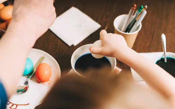 Påskdagen. Far och son målar ägg på trä bakgrund. Familjen sitter i ett kök. Förberedelse för påsk, kreativ hemlagad dekoration — Stockfoto