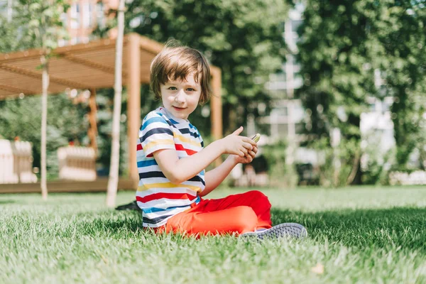 Dítě s telefonem na trávě — Stock fotografie
