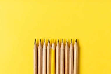 Gri kalemlerin arasından sarkan sarı bir kalem..