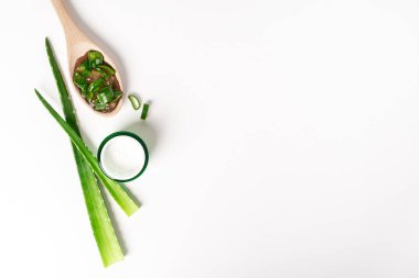 Aloe vera suyu, organik krema, jöle, havlu ve yeşil yapraklı üst manzara..