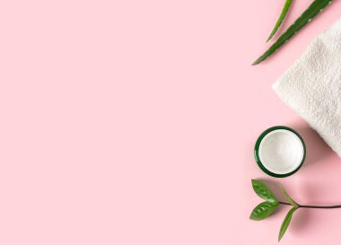 Aloe vera suyu, organik krema, jöle, havlu ve yeşil yapraklı üst manzara..