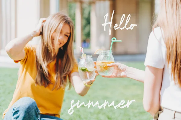 Zwei Frauen sitzen mit Limonadencocktails im Gras. — Stockfoto