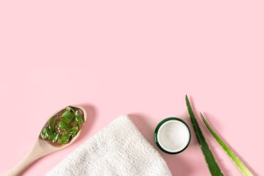 Aloe vera suyu, organik krema, jöle, havlu ve yeşil yapraklı üst manzara..