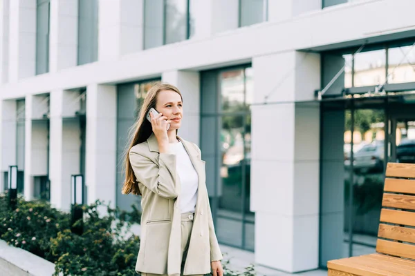 Hermosa mujer de negocios hablando por teléfono y caminando en la calle de la ciudad —  Fotos de Stock