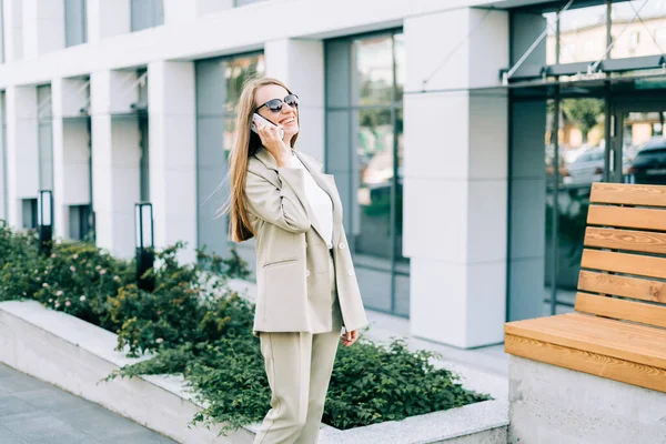 Hermosa mujer de negocios hablando por teléfono y caminando en la calle de la ciudad —  Fotos de Stock