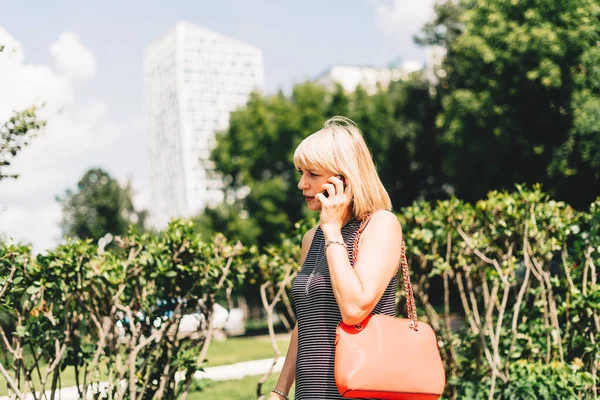 Красивая деловая женщина разговаривает по телефону и ходит по городской улице — стоковое фото