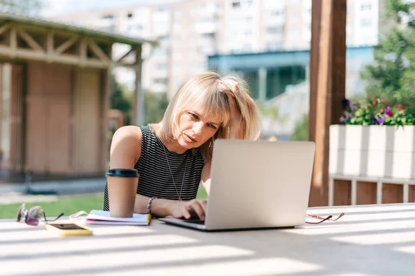 Seriöst tänkande kvinna som arbetar på laptop utanför — Stockfoto