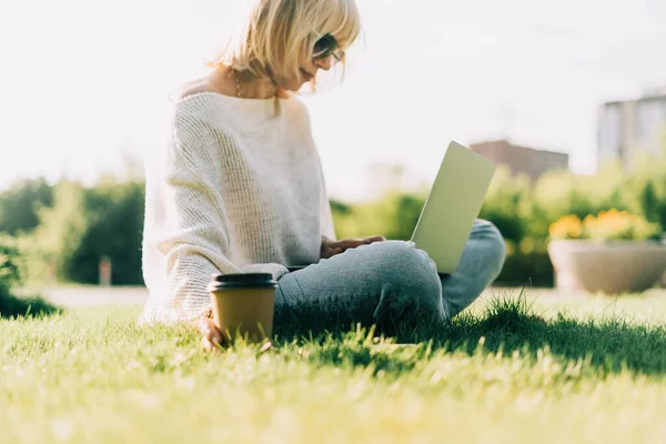 Vuxen kvinna på gräs med bärbar dator — Stockfoto