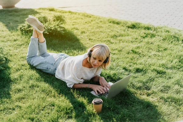 Kvinna med bärbar dator liggande på gräset — Stockfoto