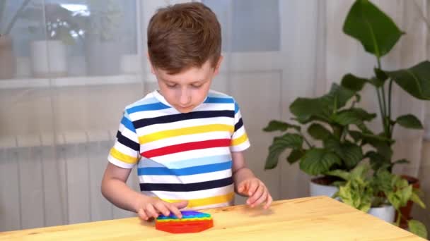 Primer plano de Kid dedos jugando con el Pop It fidget. Empuje la burbuja pop flexible fidget juguete sensorial en las manos de los niños. Alivio de estrés de silicio. Concepto de salud mental. Enfoque selectivo en el juguete — Vídeo de stock