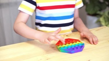 Kid 'in parmaklarını Pop It ile oynarken kapat. Popo kabarcığını esnek, hareketli duyusal oyuncağı çocukların eline ver. Silikon stres giderici. Akıl sağlığı konsepti. Oyuncağa seçici odaklanma